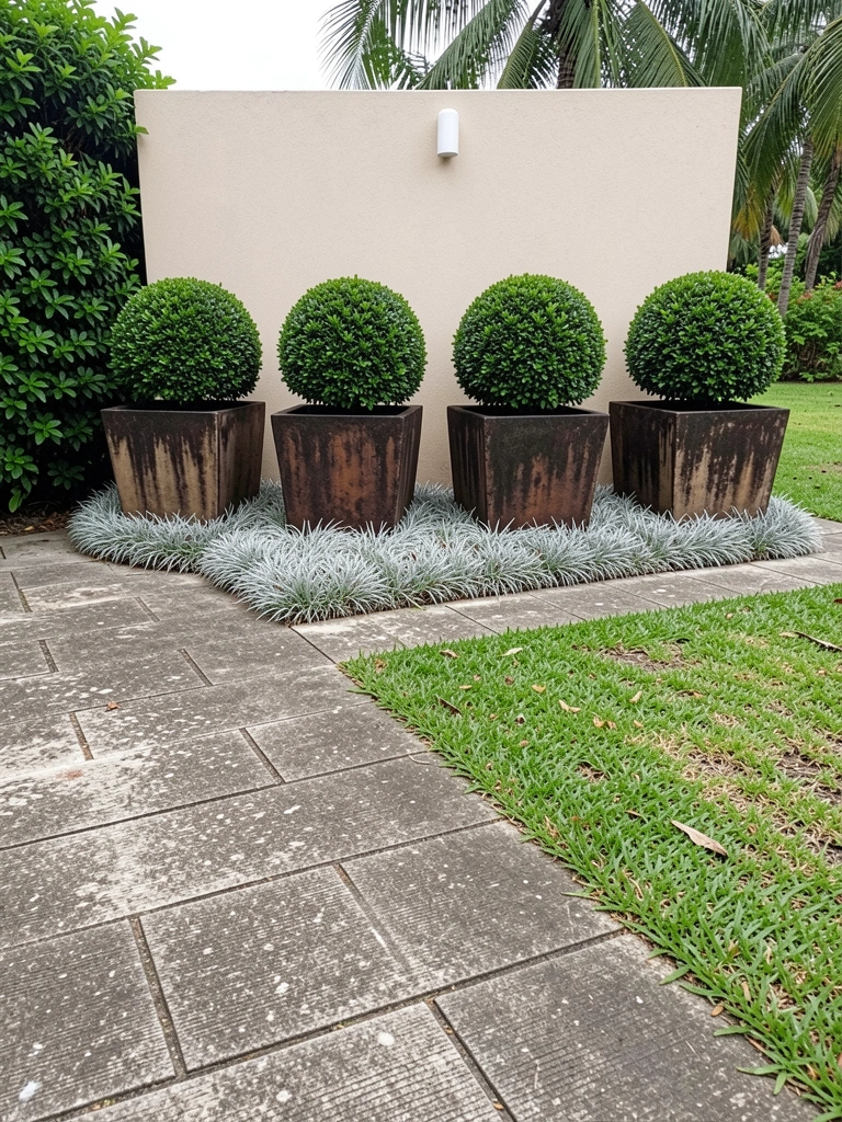 Vasos de cerâmica com plantas variadas alinhados na entrada de uma casa, parede clara ao fundo e luz natural suave.